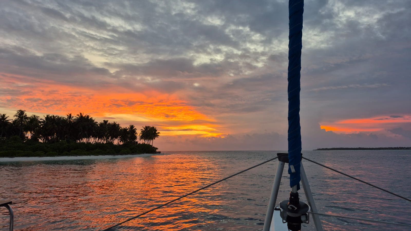 Sonnenuntergang vom Bug vor einer Palmeninsel
